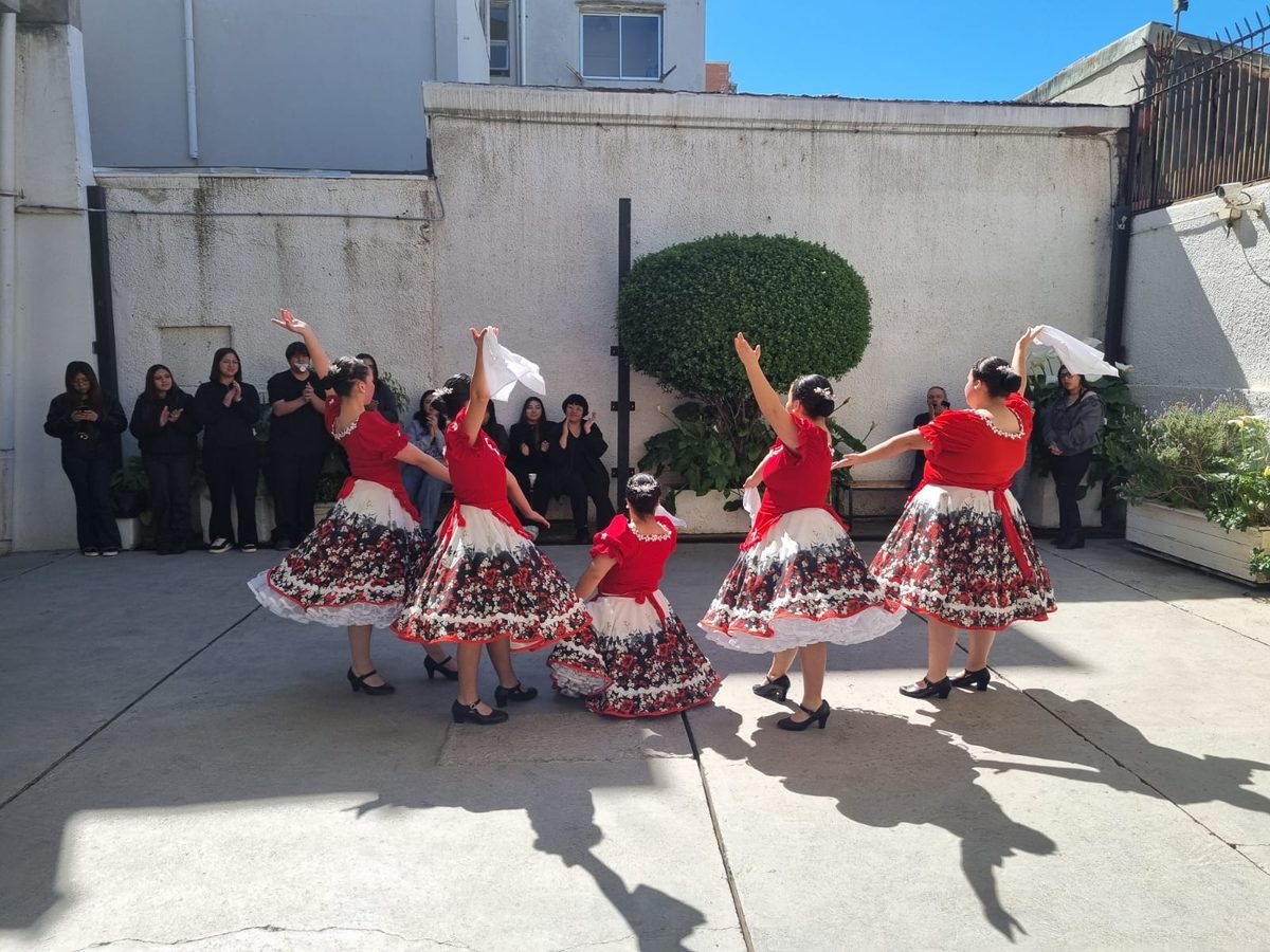 Integrantes del conjunto folclórico Tradiciones Nuevo Amanecer bailando cueca en el patio de la Escuela