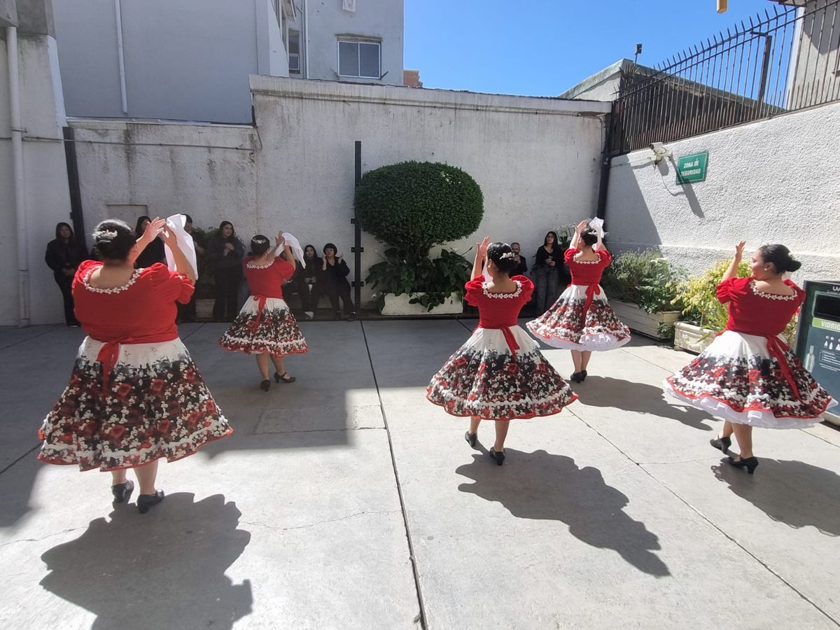 Parejas del conjunto folclórico bailando cueca ante el público asistente