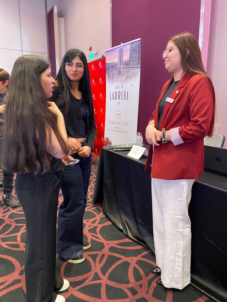 Estudiantes conversan con una representante en uno de los stands de la feria